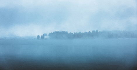 A wintery scene looking over a blue lake in the snow in New Zealand.