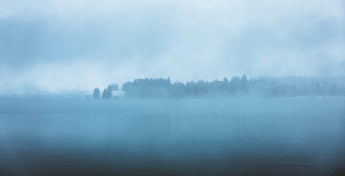 A wintery scene looking over a blue lake in the snow in New Zealand.