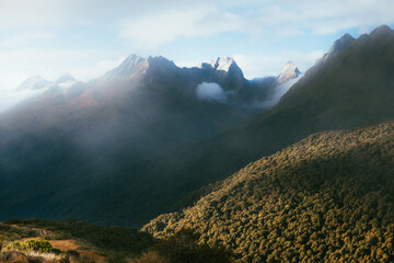 Evening light catching the side of mountains as clouds roll in.