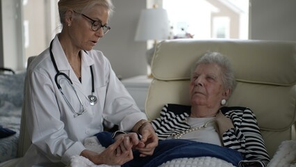 Obraz premium A nurse provides gentle care to an elderly woman in her home, ensuring comfort and attentiveness during the visit. The setting is warm and supportive.