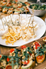 Close-up of assorted cheese platter with skewers, bruschetta on rustic table for festive appetizer
