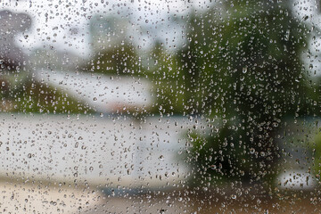 Rain drop on window glass with tree background.Rainy day.soft focus