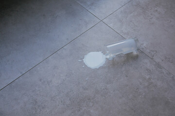  milk spilled from a glass on a flat floor surface