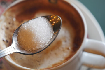 Cup of coffee with sugar spoon in warm setting