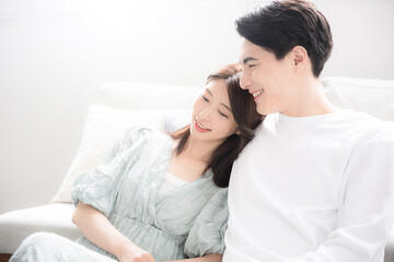 逆光の明るいリビングでリラックスする寄り添う若いカップル　夫婦や新婚さんのイメージ