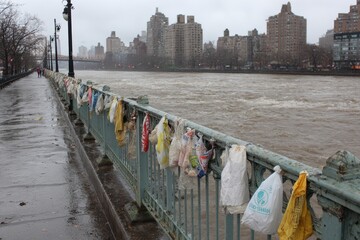Trash Bags Hanging on Bridge Rail During Rainy Day in Urban Area