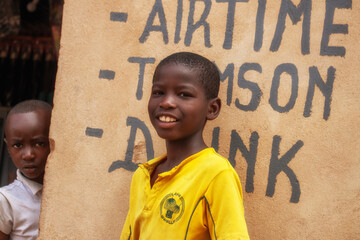 Two young African boys in a Namibian refugee camp, standing quietly against a weathered wall. A...