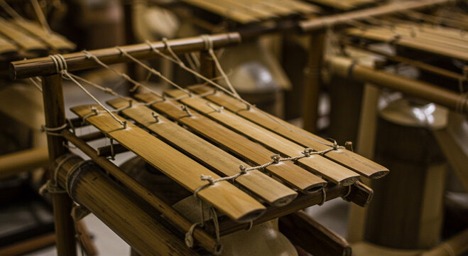 Close up of a bamboo xylophone instrument with multiple bars and string ties in a blurred setting - Powered by Adobe