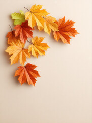 Autumn leaves in warm orange, yellow, and green tones arranged on beige background creating cozy seasonal atmosphere