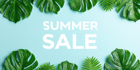 Summer sale text with tropical green leaves border on blue background, bright and fresh summer concept