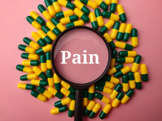 Top view medicine pill and magnifying glass with the word Pain on a pink background