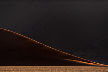 The last rays of the days light illuminates a sand dune ridge in Sossusvlei, Namibia.