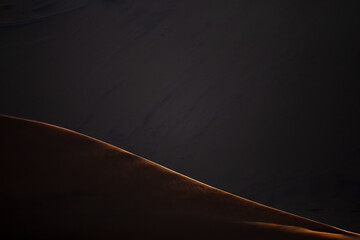 The last rays of the days light illuminates a sand dune ridge in Sossusvlei, Namibia.