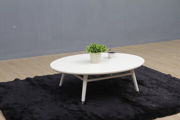 Minimal white round coffee table with small plant decor in a modern interior setting. Ideal for furniture advertising, home decor concepts, minimalist lifestyle, and interior design use.