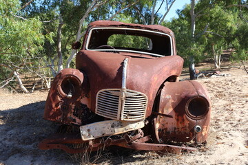 Vintage, old, rusty car abandoned in remote Australian Outback, amongst Eucalyptus trees. History, nostalgia, scrap, collection, travel and tourism