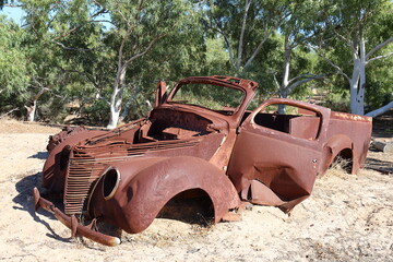 Vintage, old, rusty car abandoned in remote Australian Outback, amongst Eucalyptus trees. History, nostalgia, scrap, collection, travel and tourism