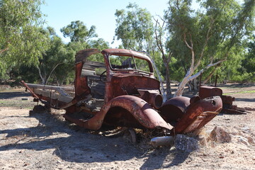 Vintage, old, rusty car abandoned in remote Australian Outback, amongst Eucalyptus trees. History, nostalgia, scrap, collection, travel and tourism