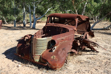 Vintage, old, rusty car abandoned in remote Australian Outback, amongst Eucalyptus trees. History, nostalgia, scrap, collection, travel and tourism