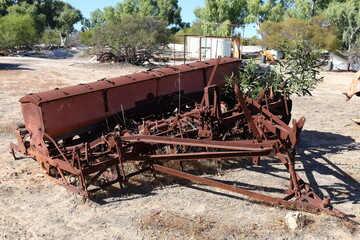 Vintage, old, rusty agriculture, farming equipment abandoned in remote Australian Outback, amongst Eucalyptus trees. History, nostalgia, scrap, collection, travel and tourism