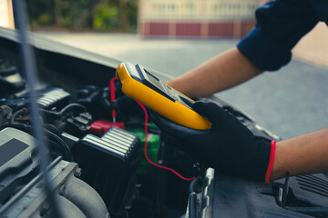 Mechanic uses electrical meter to check battery low energy problem for car care service maintenance...