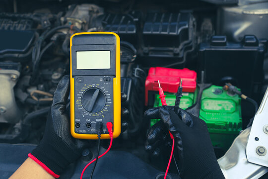 Fototapeta Mechanic uses electrical meter to check battery low energy problem for car care service maintenance and re charger or jump start or change battery replacement.