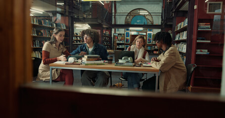 Talking, books and group of students studying in library for university test, project or exam. Knowledge, notes and friends preparing for college assignment together with scholarship at campus.