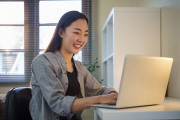 Smiling young entrepreneur working with laptop in home office.