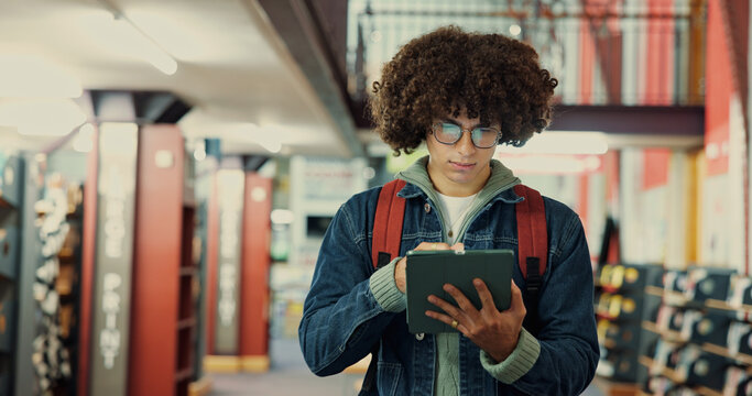 Browsing, online and man with tablet, library and student with research for exam, app and knowledge. Space, serious and person with glasses for info, read and study with tech for scholarship or learn