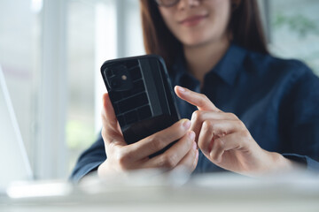 Happy young asian business woman using mobile phone for online shopping and digital banking via mobile app with laptop computer on office table. 