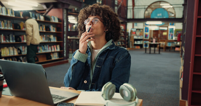 Thinking, student and man with laptop, library and idea for assignment on web, online or reflection. Contemplating, serious and person with tech for exam, knowledge or planning for project in college