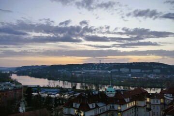Rooftop view of a picturesque cityscape with flowing river and distant hills at dusk, illuminated skyline during sunset, urban landscape and travel destination scenic beauty