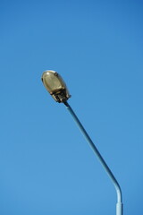 Street lamp post isolated against clear blue sky, minimalist urban lighting design, featureless background for architecture and city infrastructure concept