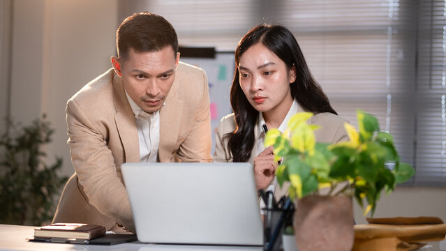 Business colleagues analyzing data together, working on business plans at desk. - Powered by Adobe