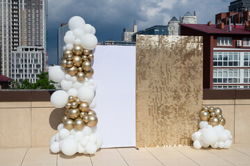 Photo zone decorated with gold and white balloons.