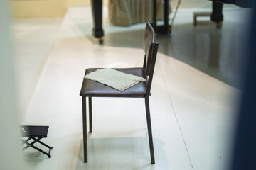 A provincial theater stage with a chair featuring cloth guitar pads and a footrest, set for a...