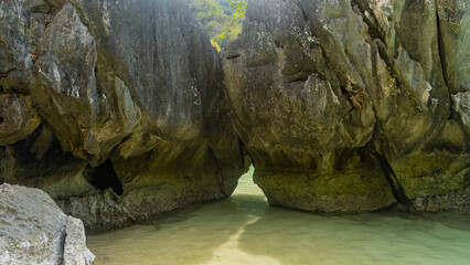 Rocks in the ocean. A narrow opening is visible between the steep, furrowed slopes of the boulders....