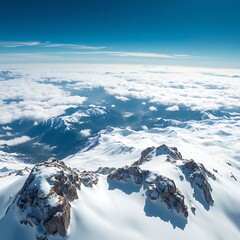 Fototapeta premium Snowy mountain peaks rise above a sea of clouds under a blue sky