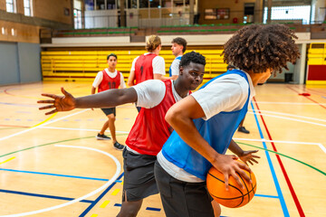 Basketball players defending and attacking during training in a gym