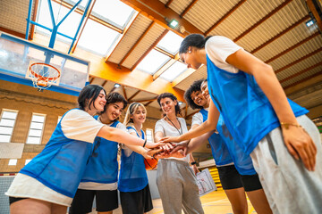 Female basketball team and coach joining hands before game