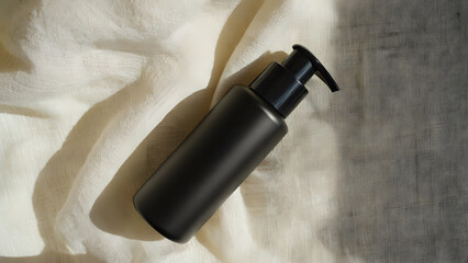 Tilted black dispenser on light linen with shadows