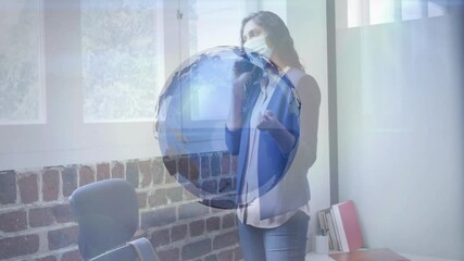 Businesswoman holding smartphone by window, initiating rotating globe while picking up coffee mug - Powered by Adobe