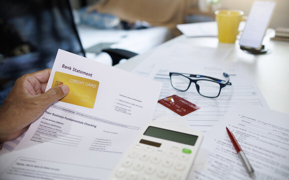 asian man holding credit card with bank statement calculating expenses and checking bank statement from credit card debt