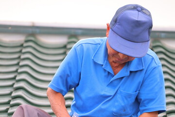 瓦屋根で作業する70代の日本人職人｜高齢でも現役の伝統技術者