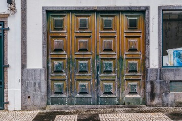 Ornate Vintage Wooden Door With Worn Paint Texture. European architecture, old entrance, weathered timber, rustic facade, historic urban detail. Highlights intricate paneling and textured surface.