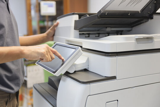 Office men use photocopy or copier machine at workplace is equipment for make a copy paper or photocopier for scanning document and photocopying service maintenance concepts.