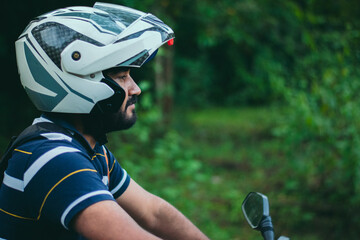 Closeup of young guy enjoying motorbike ride in the forest.