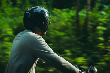 Closeup of young guy enjoying motorbike ride in the forest.