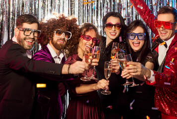 Happy friends celebrating holiday during evening party, drinking champagne and dancing with fun, creating joyful moments in a lively setting with focus on connection and entertainment.