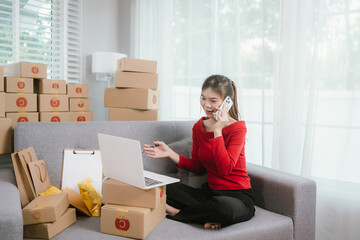 A young woman is comfortably working on a laptop on a sofa, surrounded by numerous shipping boxes, indicating an e-commerce business from home.