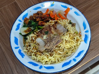 Guring beef noodle soup, equipped with delicious toppings, served on a traditional Indonesian iron plate.